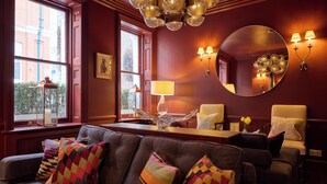 A cozy living room with a sofa, armchairs, a coffee table, and a large mirror. - Durrants Hotel (London)