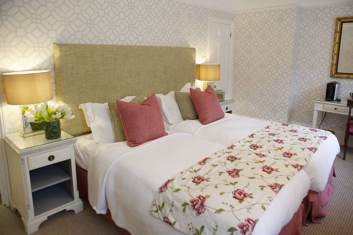 Une chambre d’hôtel avec un grand lit, deux tables de chevet avec des lampes, une petite table d’appoint et un miroir au mur.