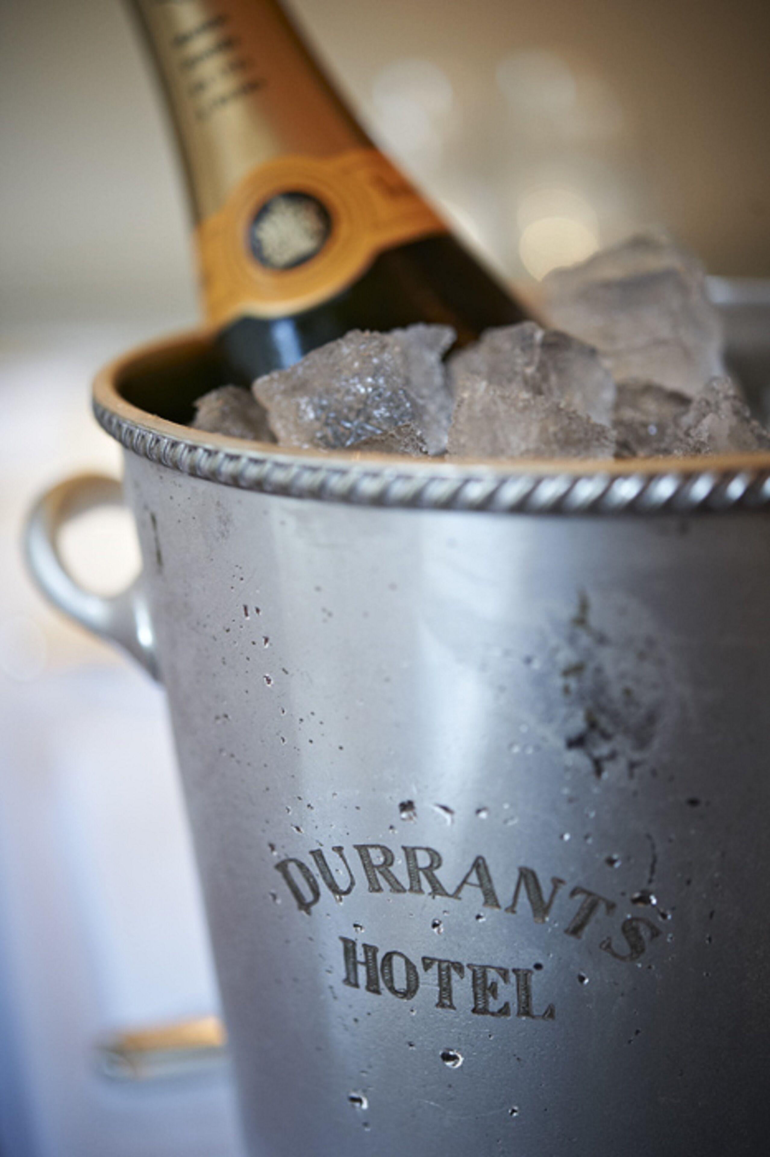 A metallic bucket with the inscription "Durrants Hotel" and ice cubes inside.