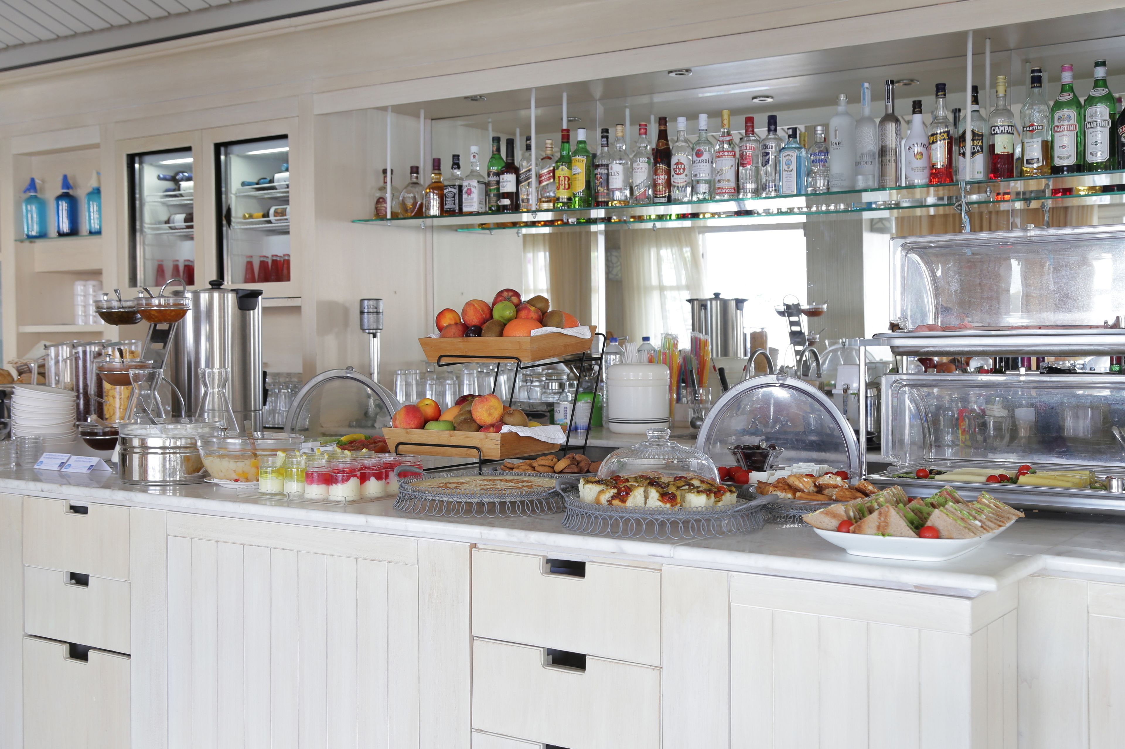 Un bufé con diversos alimentos, una selección de bebidas y una vitrina.