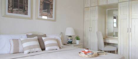 A bedroom with a bed, pillows, a bedside table with a lamp, a chair, and a wardrobe.