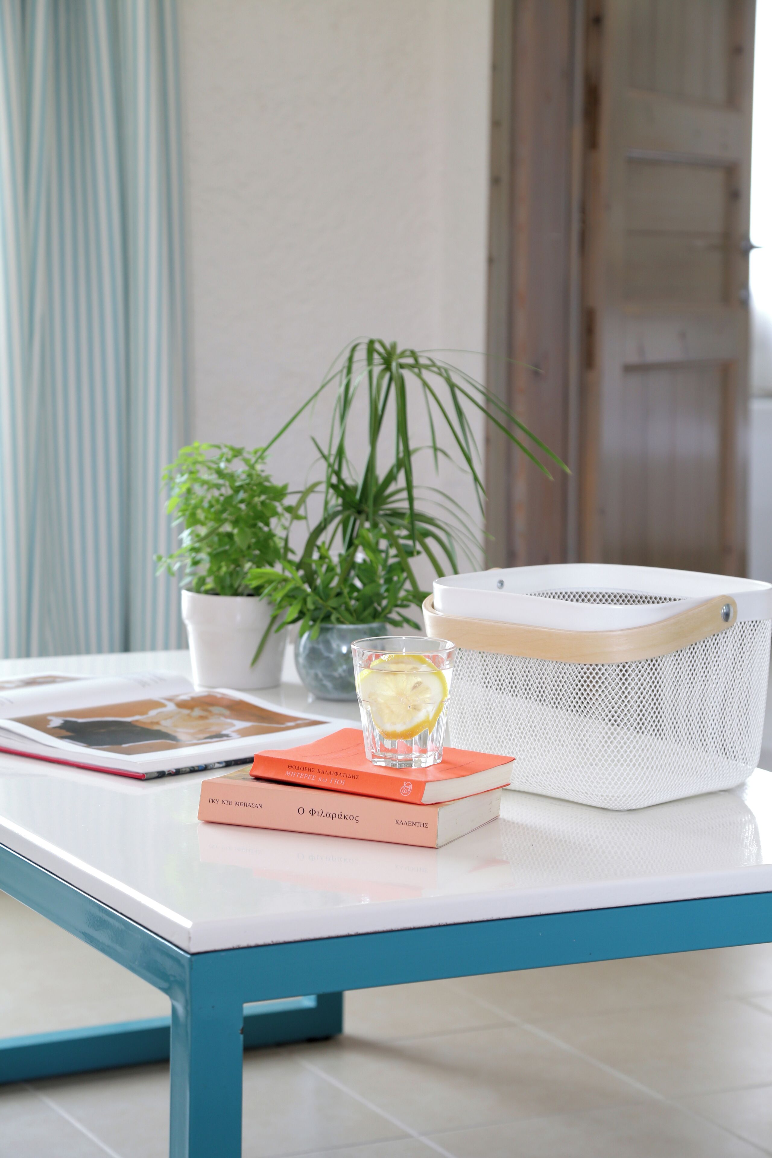 A table with a book, a glass of water, and a white basket.