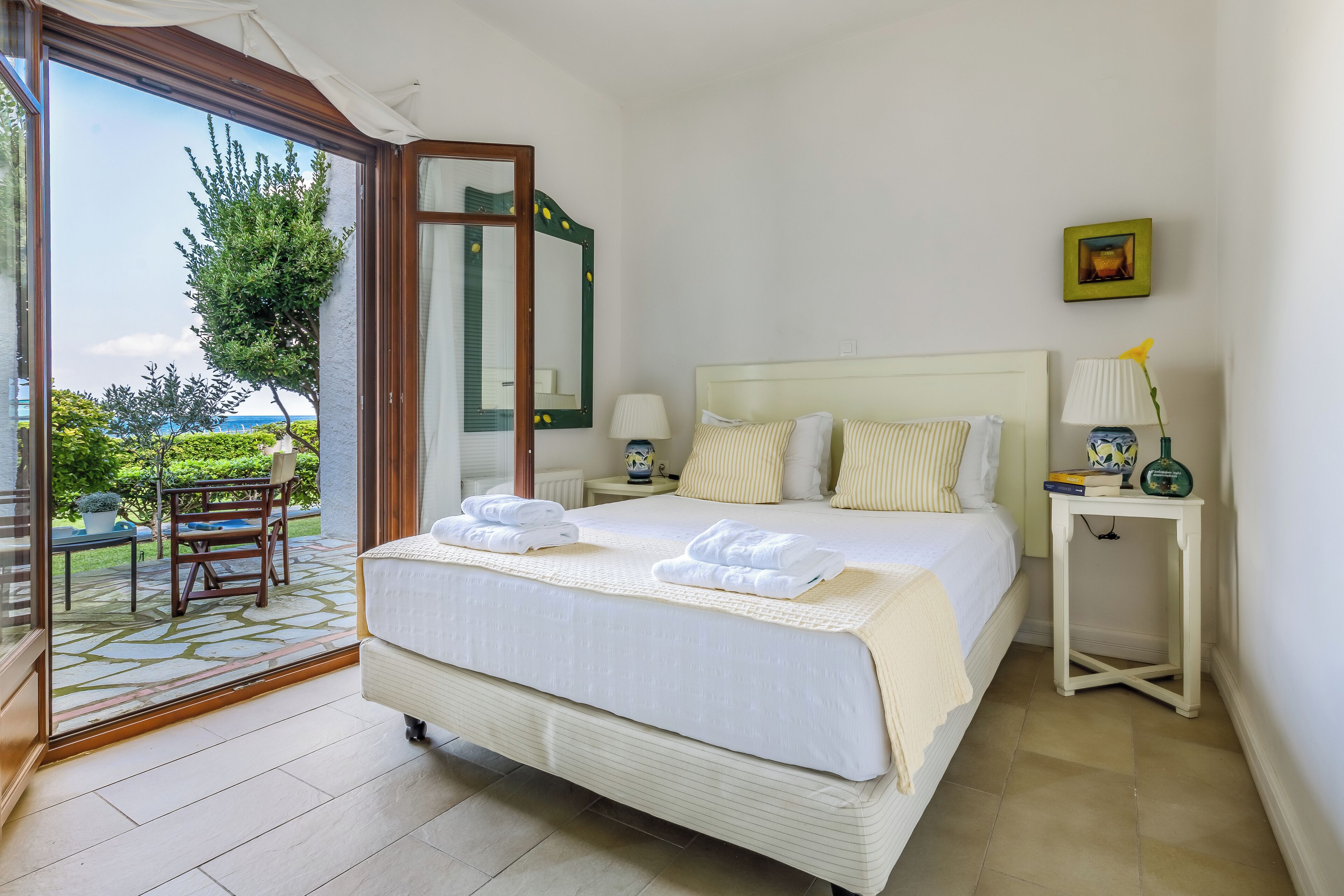 Habitación de hotel con cama, mesita de noche, silla y vistas al exterior.