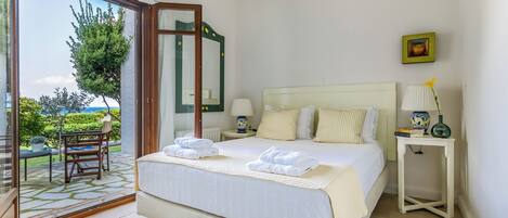 A hotel room with a bed, a nightstand, a chair, and a view of the outdoors.