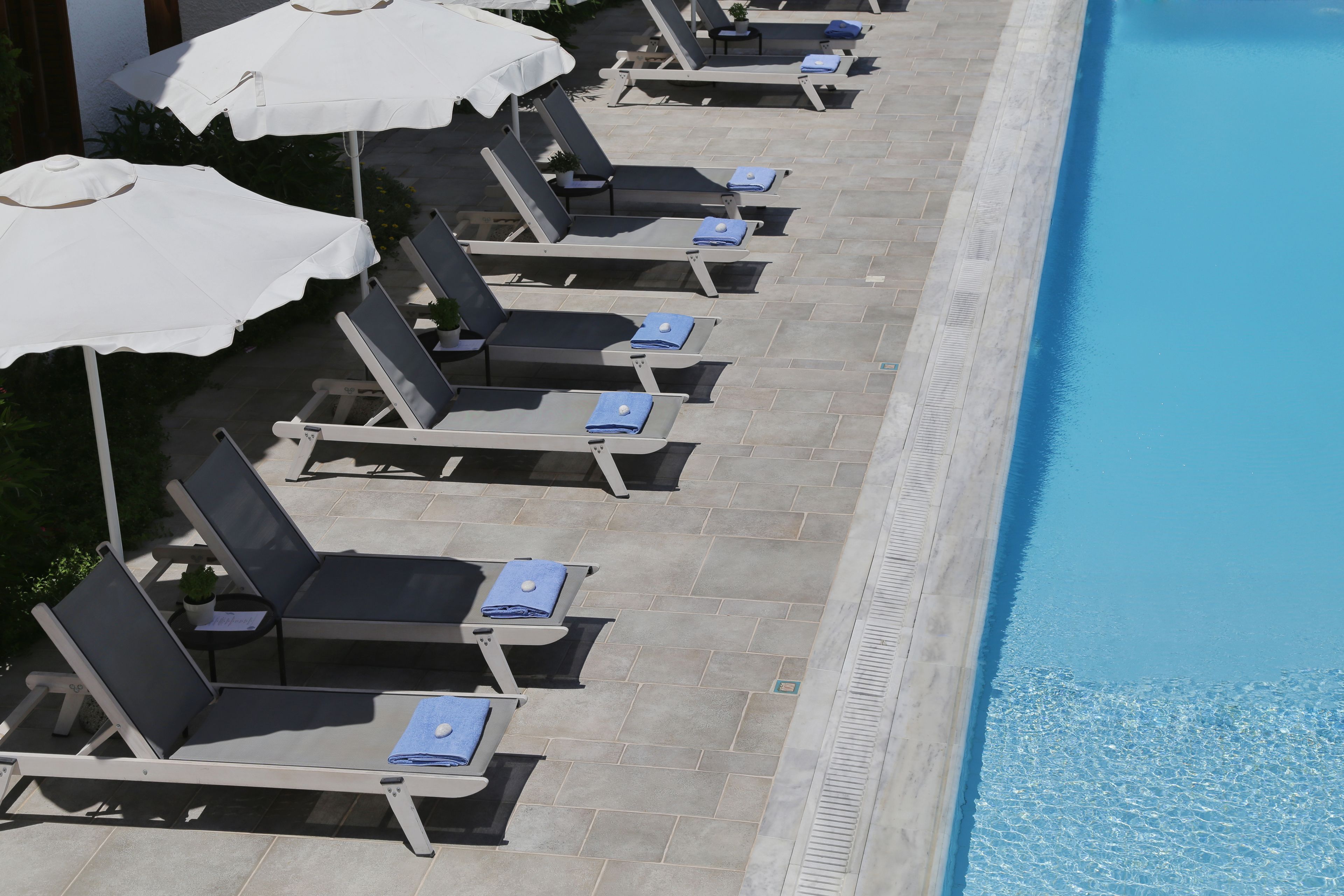 A poolside area with sun loungers and umbrellas.