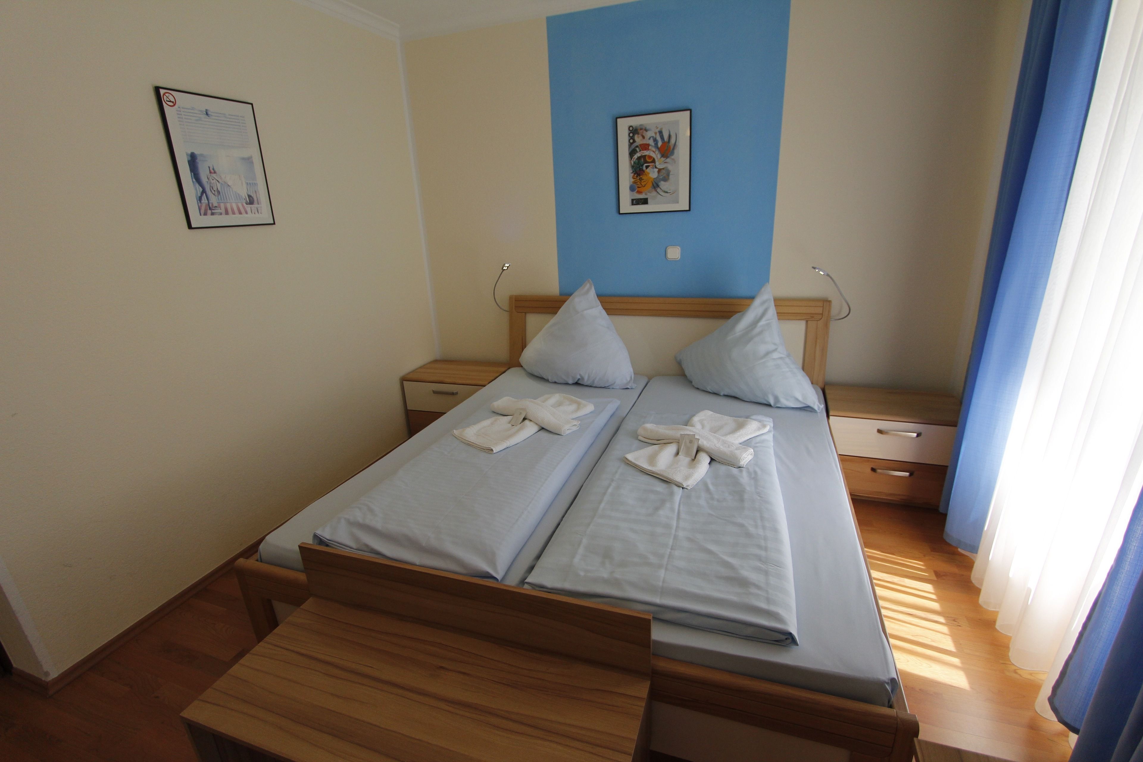 Ein Doppelbett mit zwei Kissen und einer hölzernen Bank davor.