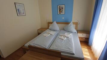 Ein Doppelbett mit zwei Kissen und einer hölzernen Bank davor.