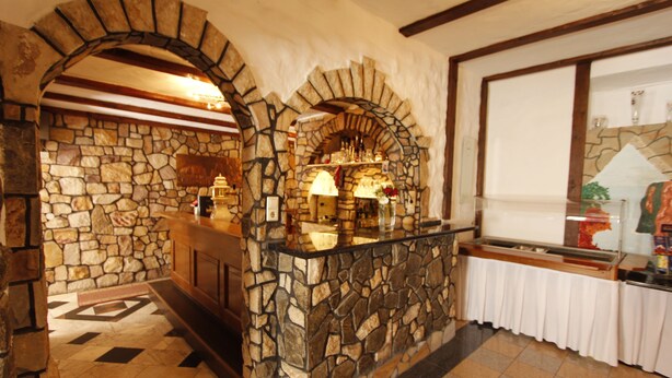 A stone-walled reception area with a counter and a display case. - Hotel Restaurant Adria - Stuben (Urbar)