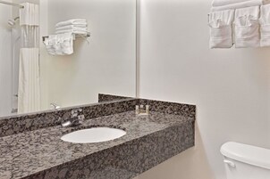 Un baño con lavamanos de encimera de granito, un espejo y un inodoro.