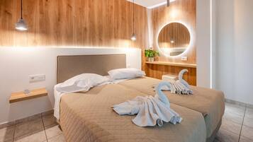 Una habitación de hotel moderna con una cama grande, paneles de madera, un espejo redondo y una mesita de noche con una planta.