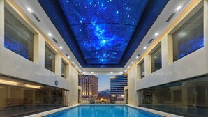 A modern indoor swimming pool with a starry sky ceiling and city views. - Poly Plaza Hotel (Beijing)