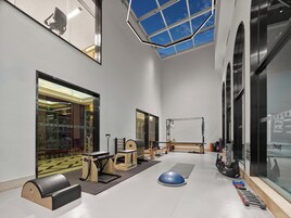 A spacious indoor area with exercise equipment, a skylight, and large windows.