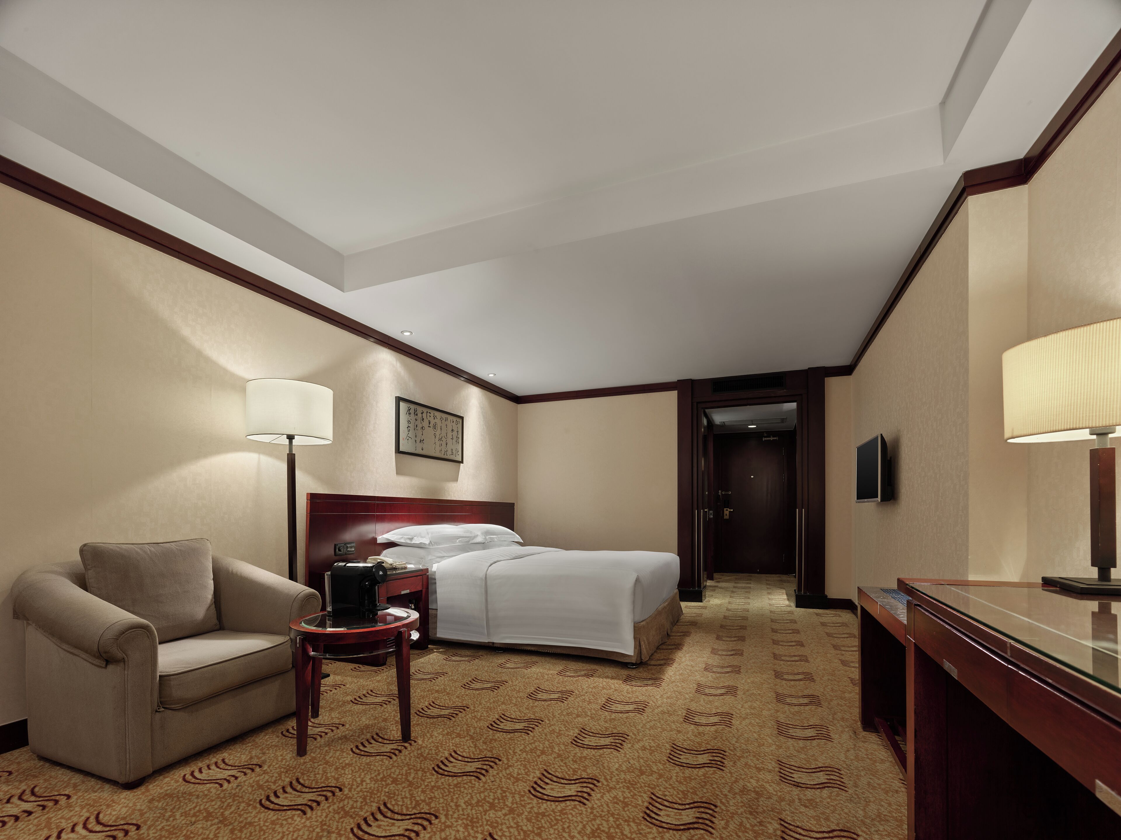 Una habitación de hotel con cama, sofá, escritorio y lámpara.