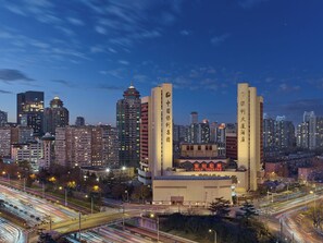 A cityscape at dusk with illuminated buildings, including a prominent theater with Chinese characters. - Poly Plaza Hotel (Beijing)