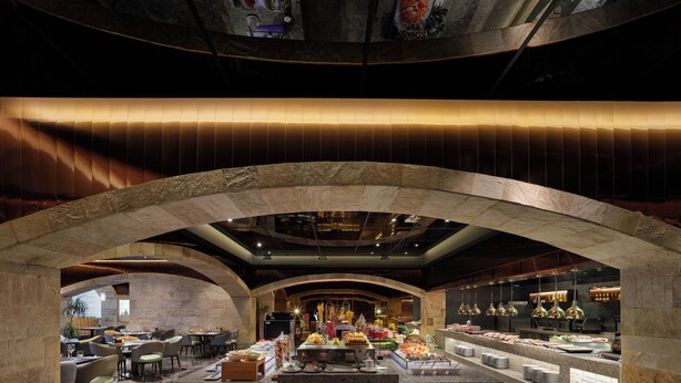 A restaurant with a stone archway, a buffet area with various food items, and seating arrangements. - Poly Plaza Hotel (Beijing)