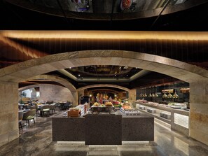 A restaurant with a stone archway, a buffet area with various food items, and seating arrangements. - Poly Plaza Hotel (Beijing)