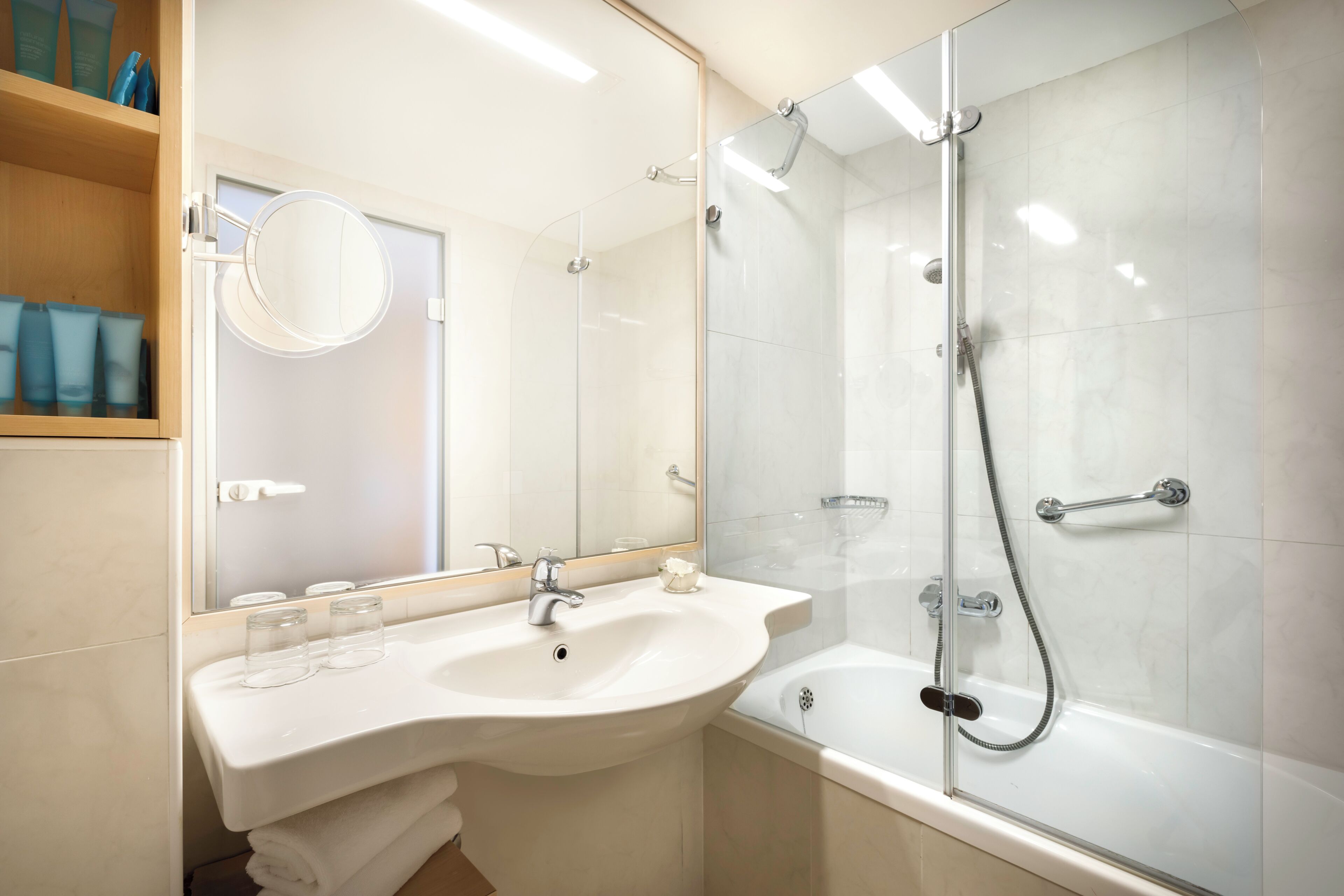 A modern bathroom with a sink, mirror, and glass-enclosed shower.
