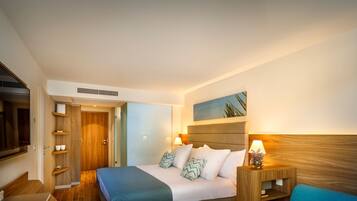 A hotel room with a bed, bedside table, lamp, and a television.