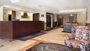 A reception area with a reception desk, a chair, and a couch. - Days Inn & Suites by Wyndham Langley (Langley)