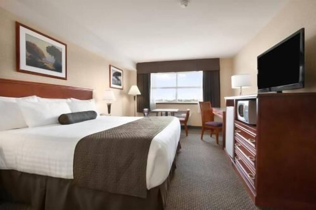 Una habitación de hotel con una cama, un escritorio, una silla, un televisor y una ventana.