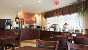 A hotel restaurant with a buffet setup, including a coffee machine, a microwave, and a variety of food items displayed on the counter. - Days Inn & Suites by Wyndham Langley (Langley)