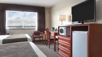 A hotel room with two beds, a desk with a chair, a television, a microwave, and a refrigerator.