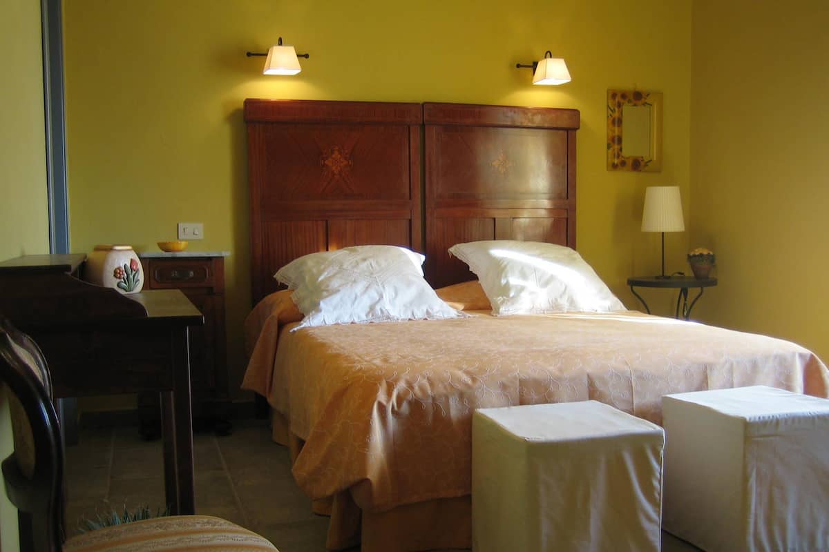 Une chambre à coucher avec une tête de lit en bois, deux tables de chevet, une chaise et deux lampes de chevet.