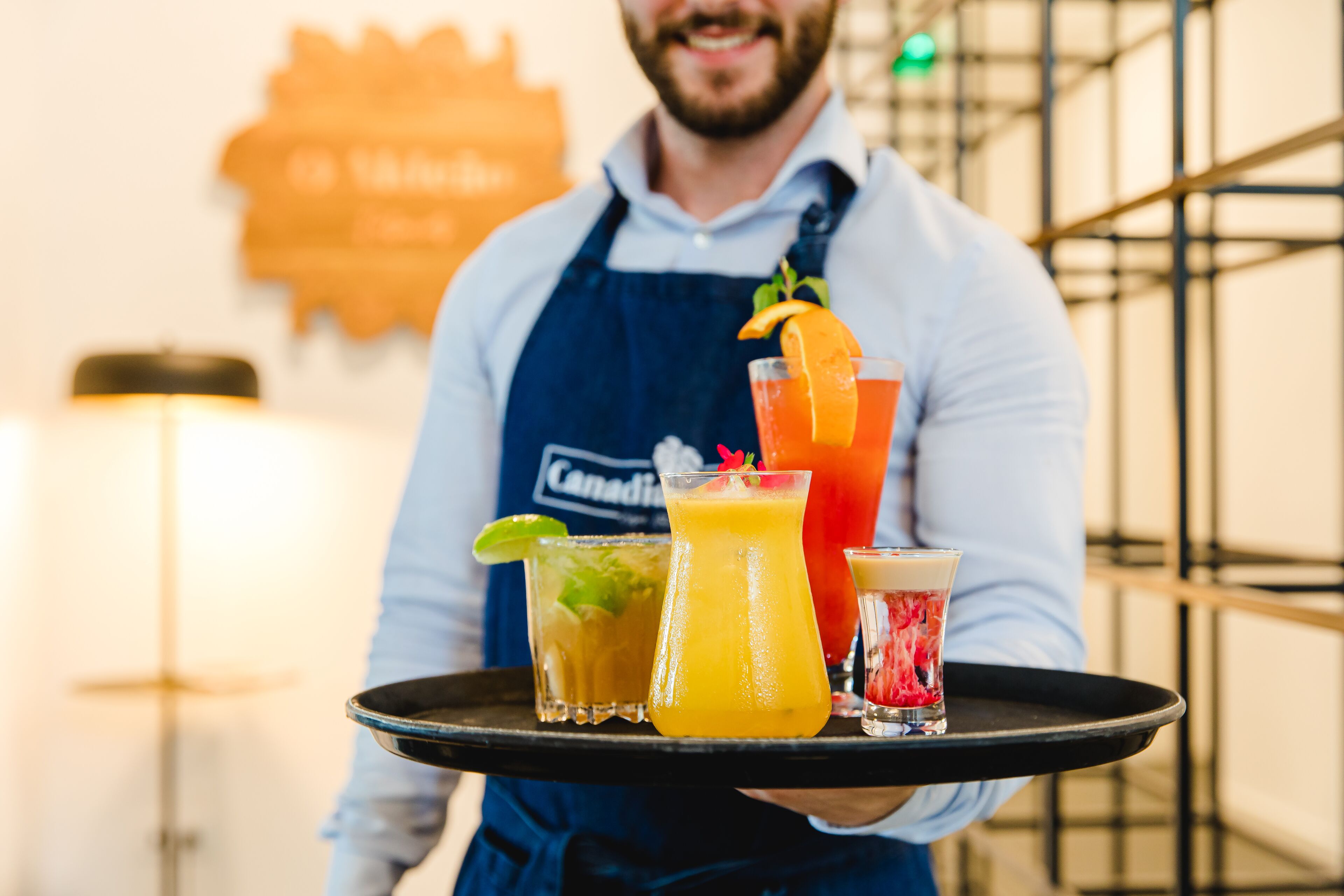 A person holding a tray with various drinks.