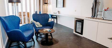 A modern living room with blue armchairs, a coffee table, and a TV mounted on the wall.