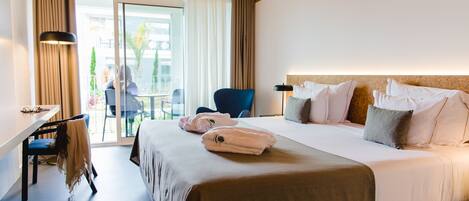 A hotel room with a bed, a desk, a chair, and a view of the outdoors.