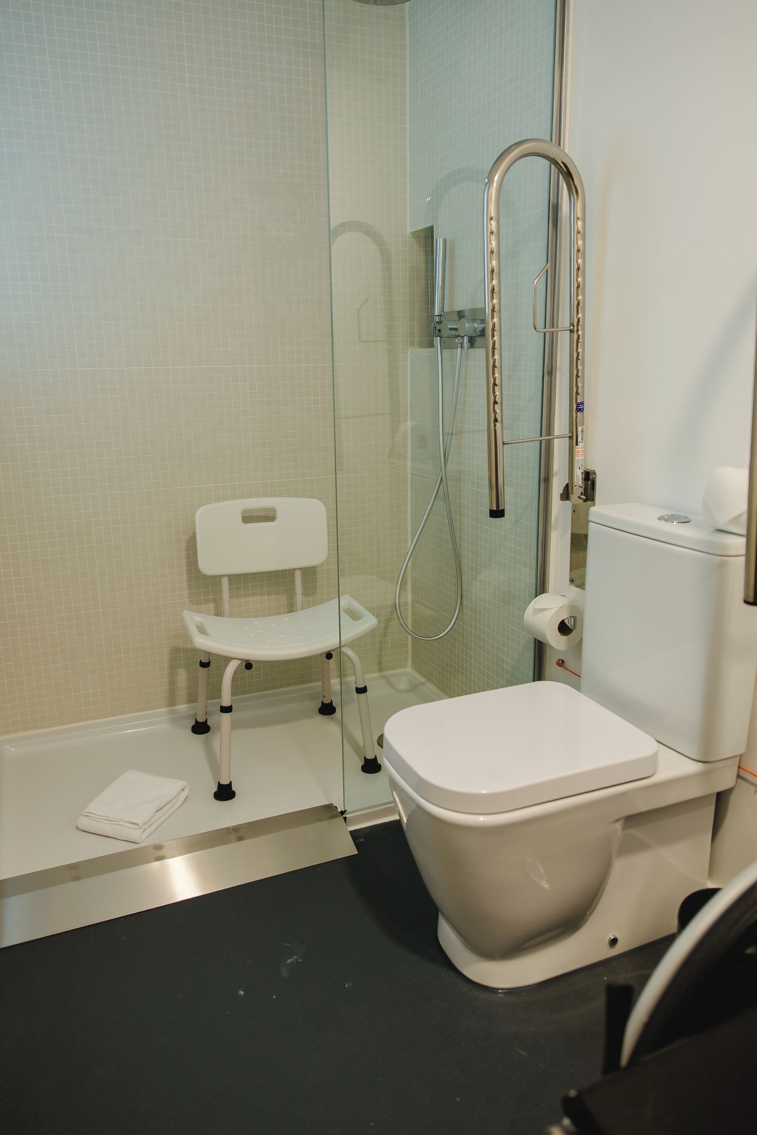A bathroom with a white toilet, a glass shower enclosure, and a white baby changing station.
