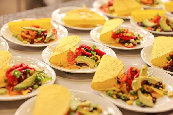 A table with multiple plates of food, each containing a tortilla, vegetables, and a yellow sauce.
