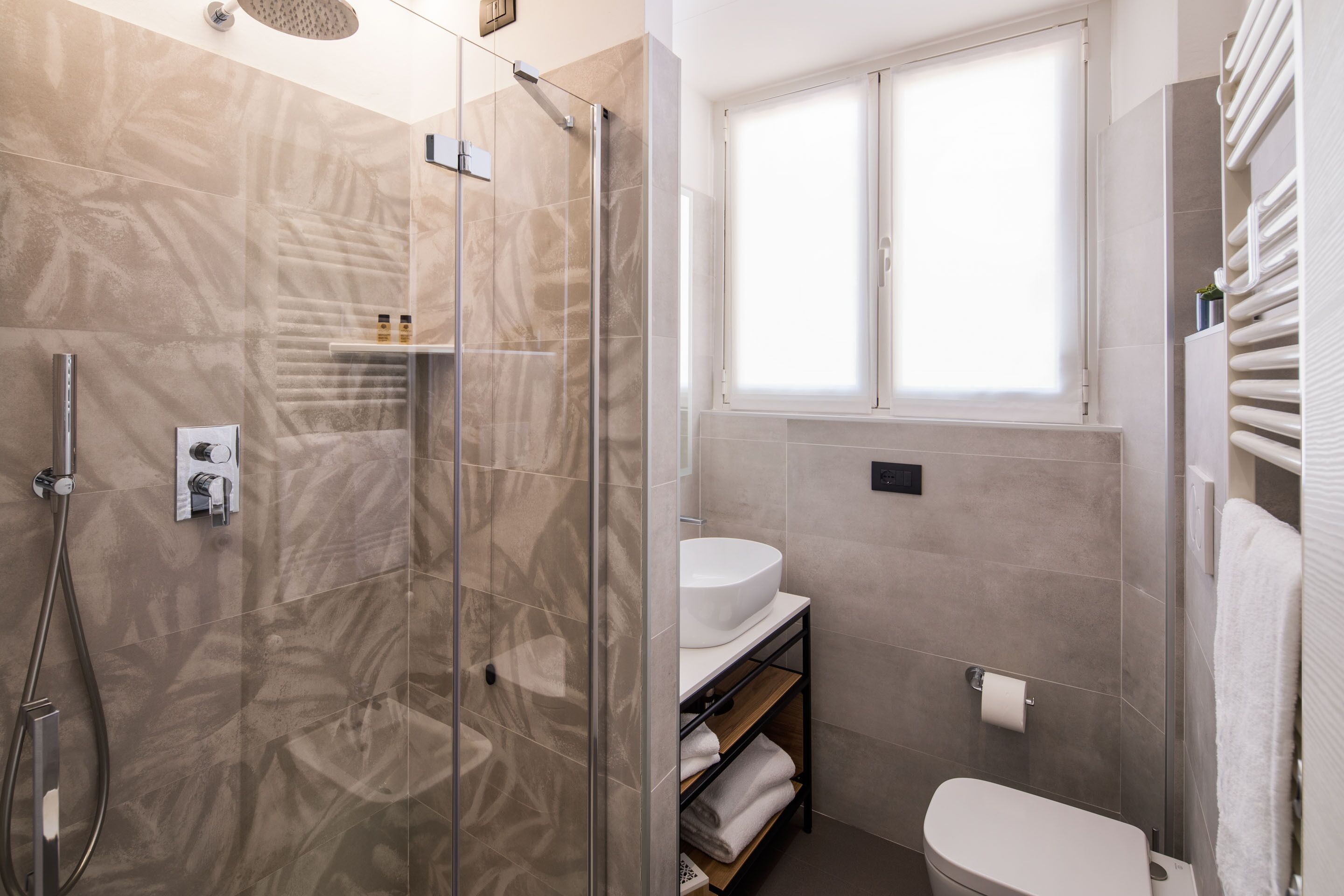 A modern bathroom with a glass-enclosed shower, a white sink, and a toilet.