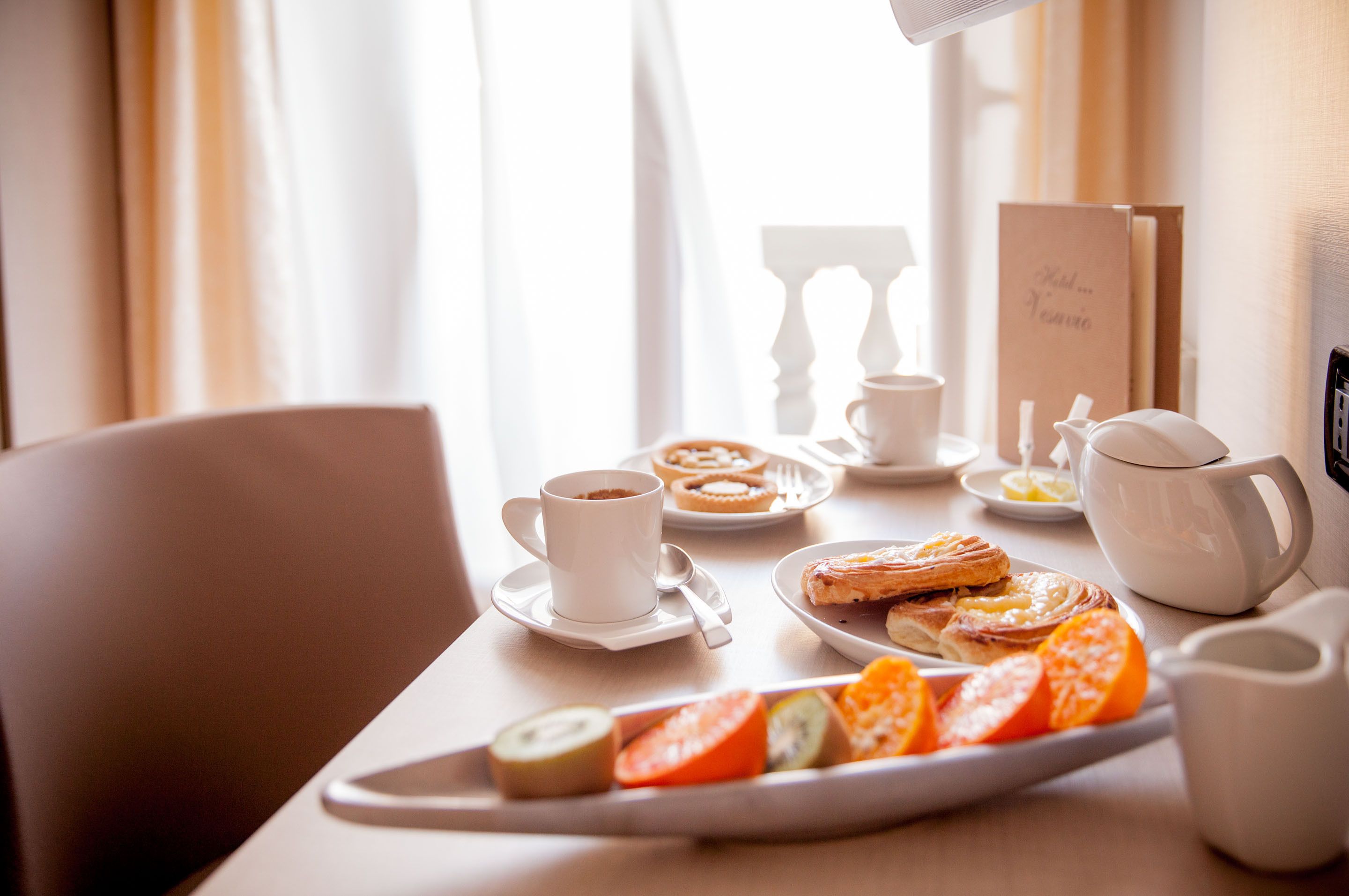 Un desayuno con una bandeja de pasteles, una taza de café y una tarjeta de menú.