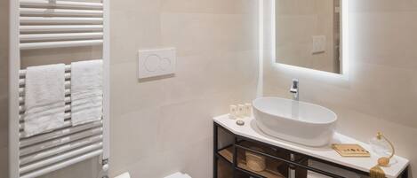 A modern bathroom with a white sink, a mirror, and a towel rack.