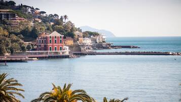 A coastal town with buildings along the waterfront, a bridge, and a clear view of the sea.
