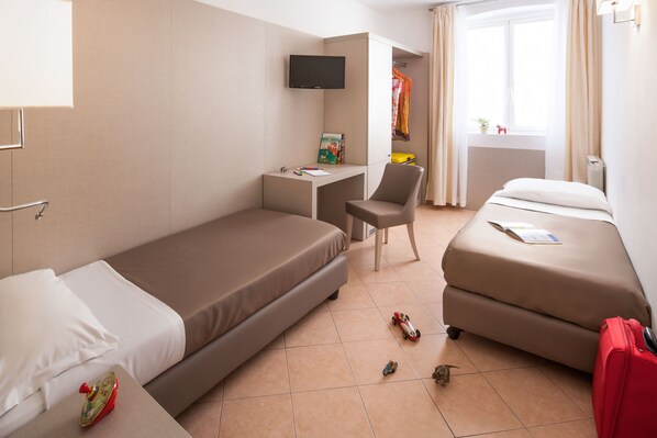 A hotel room with a bed, a desk with a chair, a TV, and a suitcase.