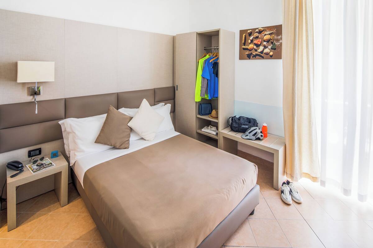 A hotel room with a bed, a nightstand, a wardrobe, and a desk.