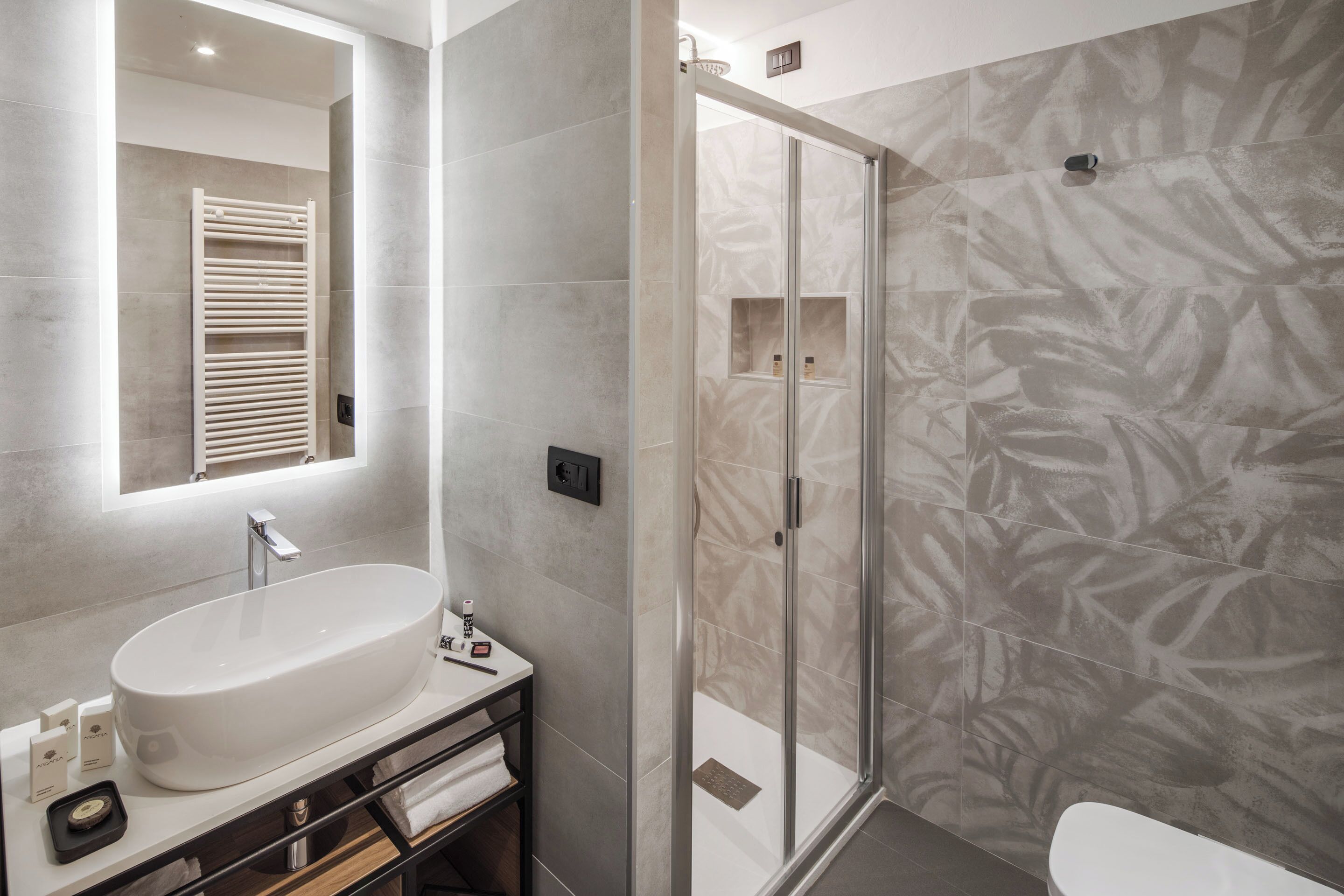 Un bagno moderno con un ampio lavabo ovale, box doccia in vetro e un water.