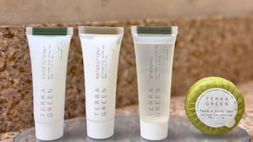 Tres tubos blancos de productos Terra Green sobre una superficie de vidrio transparente.
