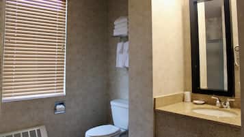 Une salle de bain comprenant des toilettes, un lavabo, un miroir et un porte-serviettes.