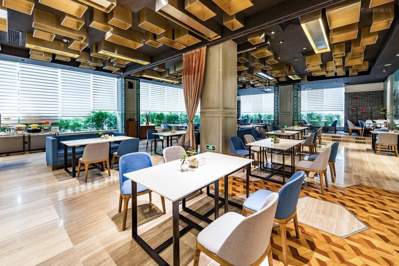Un espace repas moderne avec des tables et des chaises, de grandes fenêtres et un sol à motifs.