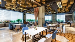 Un espace repas moderne avec des tables et des chaises, de grandes fenêtres et un sol à motifs.