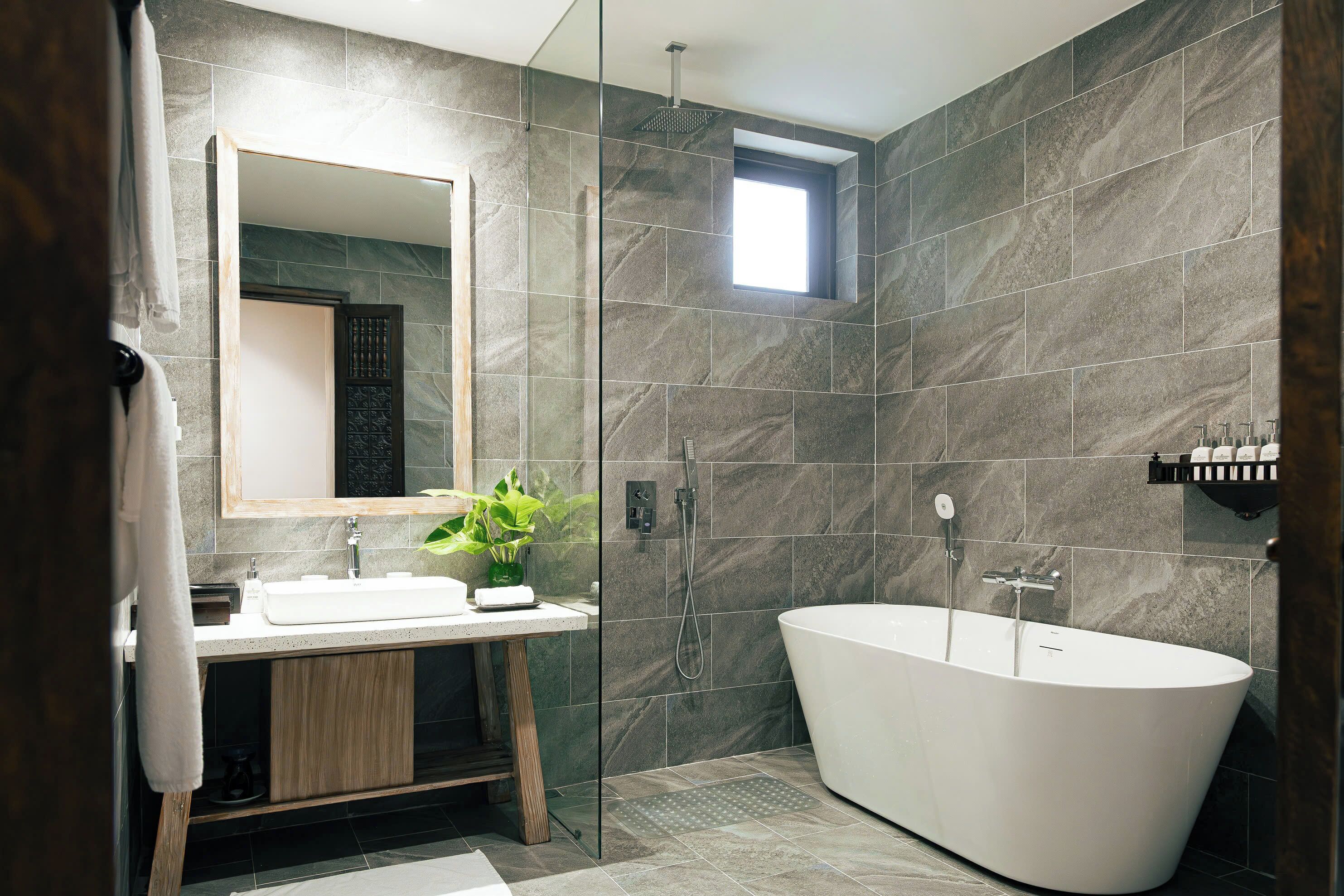 A modern bathroom with a freestanding bathtub, a glass shower enclosure, and a large mirror above the sink.