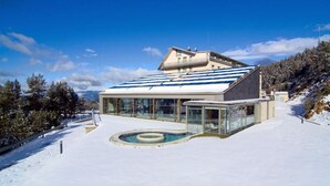 A modern building with a glass facade, a pool, and a snowy landscape.