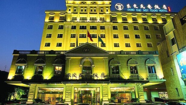 A large, multi-story hotel with a prominent entrance and a flag on the roof. - Dong Jiao Min Xiang (Beijing)