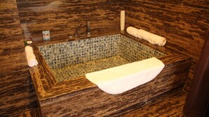 A rectangular bathtub with a mosaic tile interior, surrounded by dark wooden flooring. - Dong Jiao Min Xiang (Beijing)