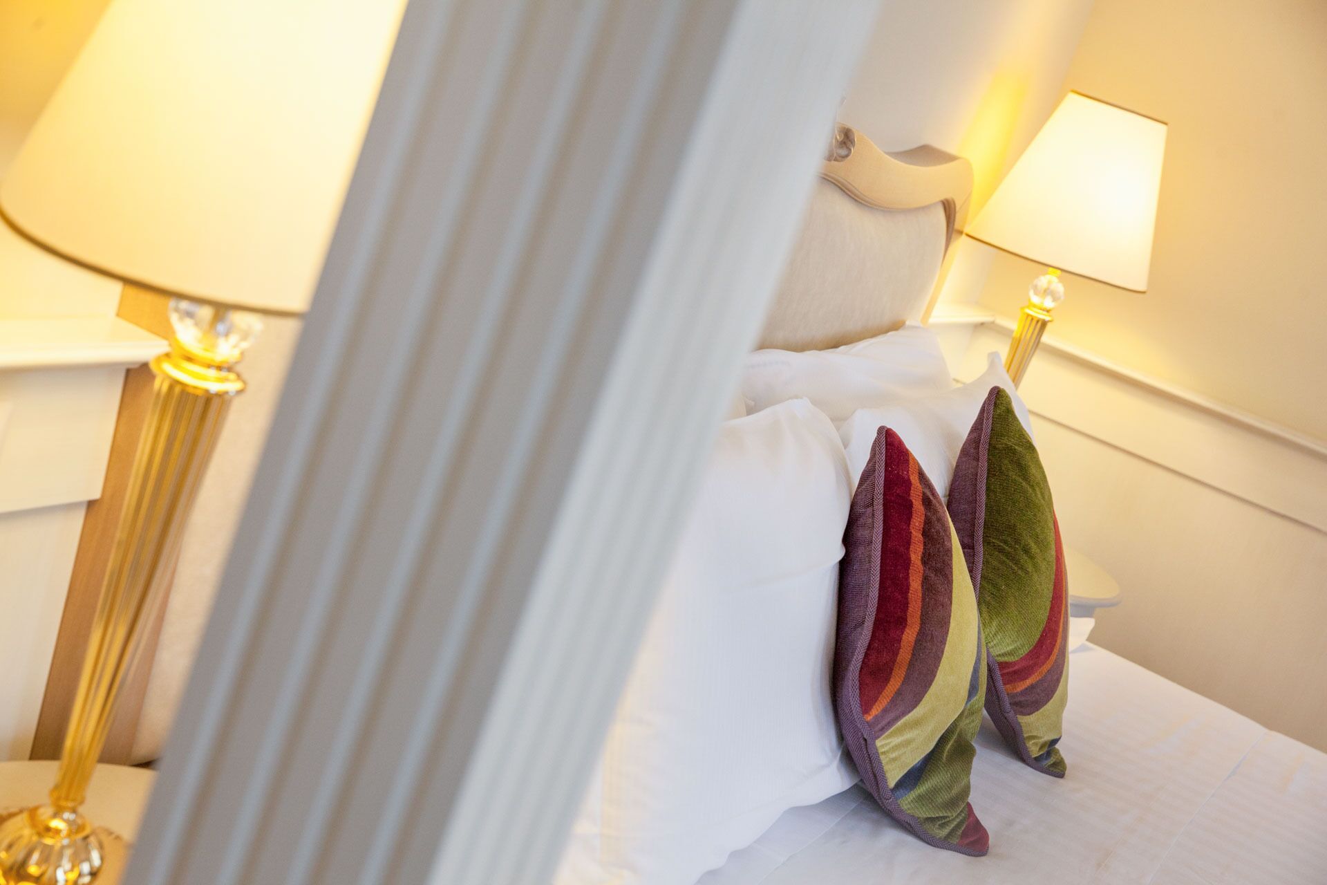 Una habitación de hotel con cama, almohadas y dos lámparas de noche.