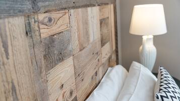 Cabecera de madera rústica con un almohadón blanco y otro almohadón estampado en una cama.