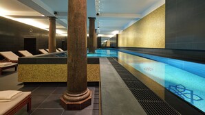 A modern spa area with a pool, lounge chairs, and a large column. - Hotel De Rome Berlin (Berlin)